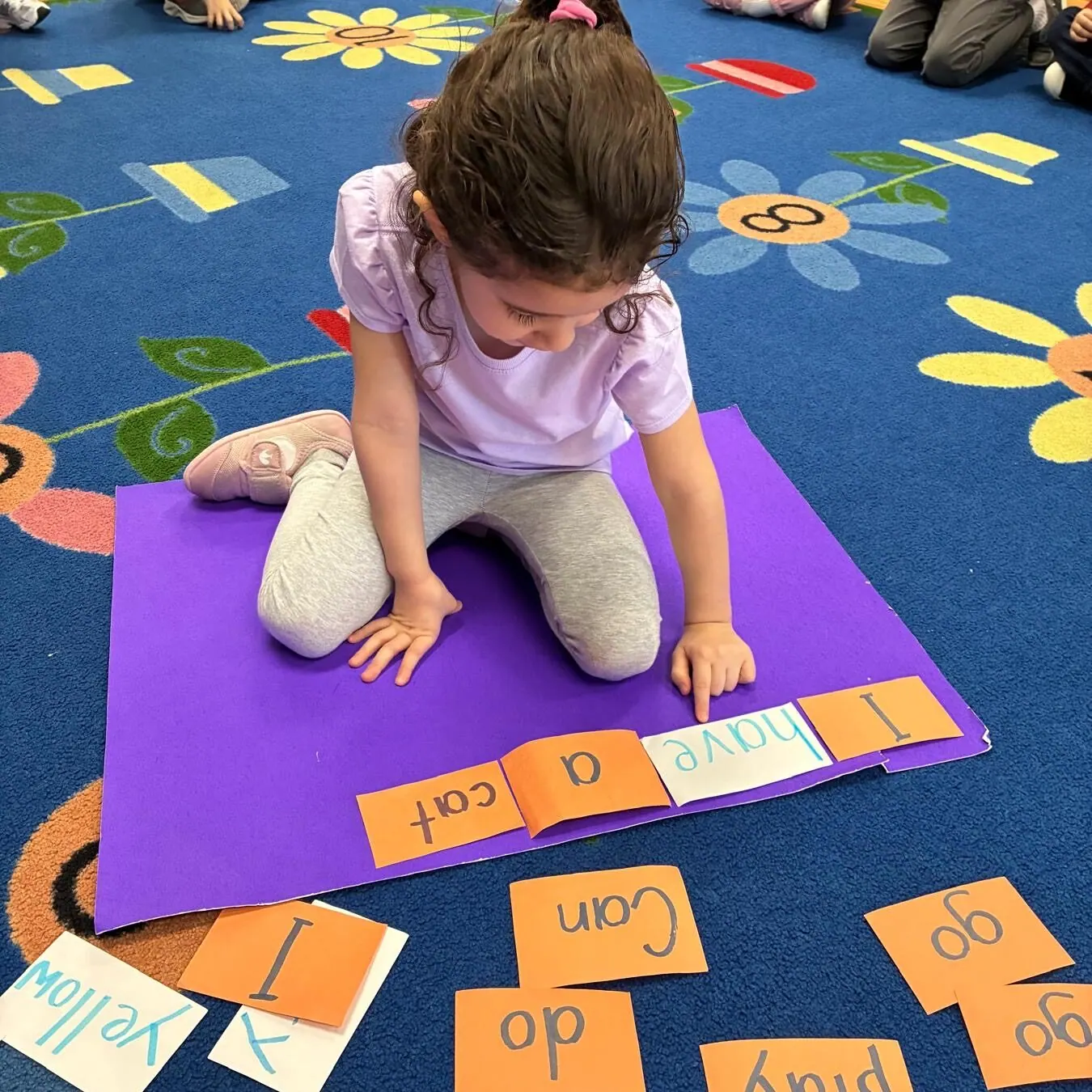 Child practicing sight words on learning mat at kindergarten