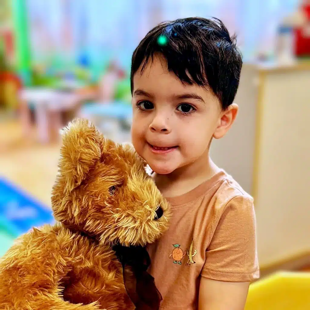 Toddler hugging a teddy bear at Fantasy Island daycare near Edison Park